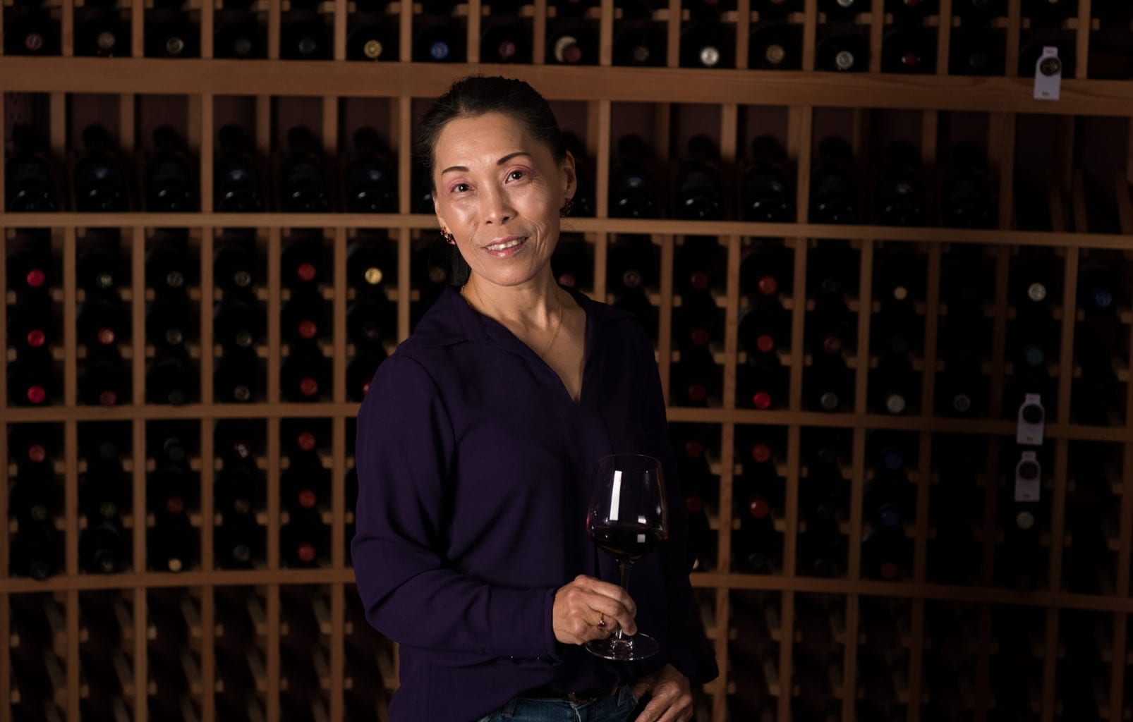Yun Chu with a glass of wine in the cellar